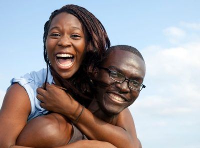a man carrying his woman on his back a happy black couple