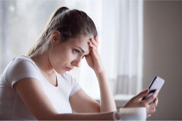 A woman looking at a phone waiting for a call