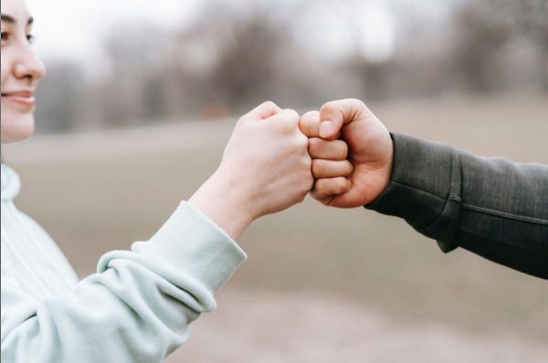 a man and a woman doing a fist bump to show confidence