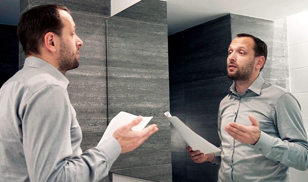 man speaking to himself before a mirror
