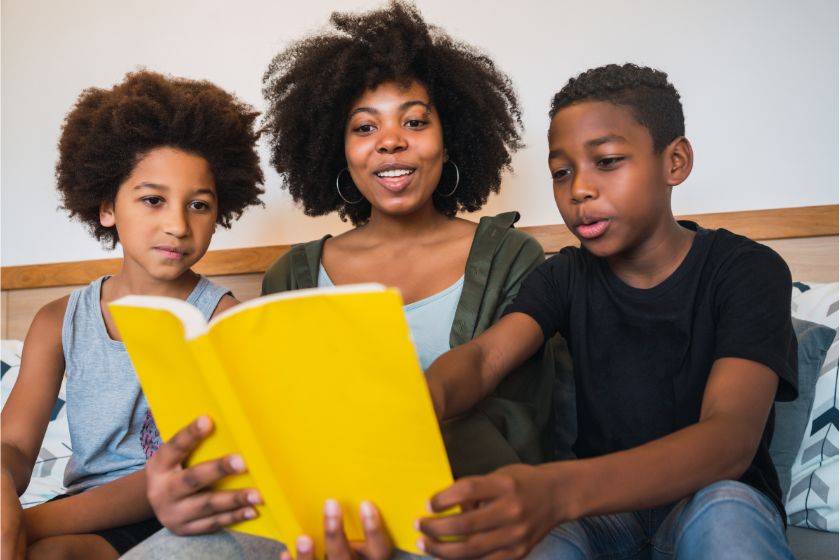 a black mother reading with her kids at home