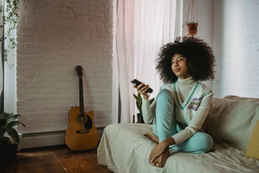 an african american woman watching a movie at home