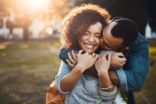 A black happy couple in an affectionate hug in a field
