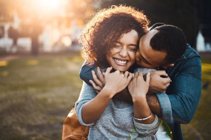 A black happy couple in an affectionate hug in a field