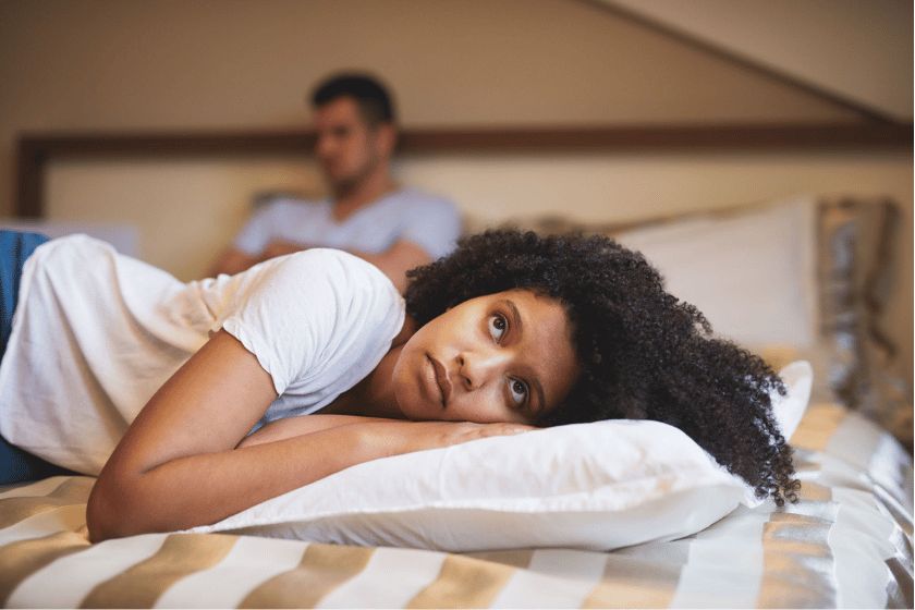 a sad African American woman with her partner behind her - couple fighting
