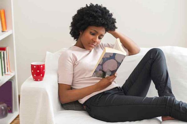 An African American lady reading on couch at home