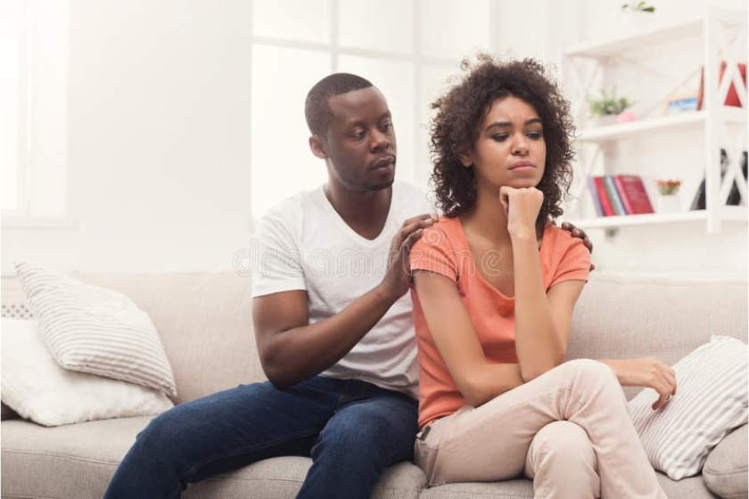 A young African American couple quarrelling with the husband pleading with the wife