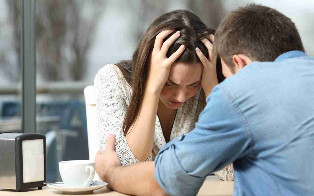 A white woman feeling sad and a man comforting her